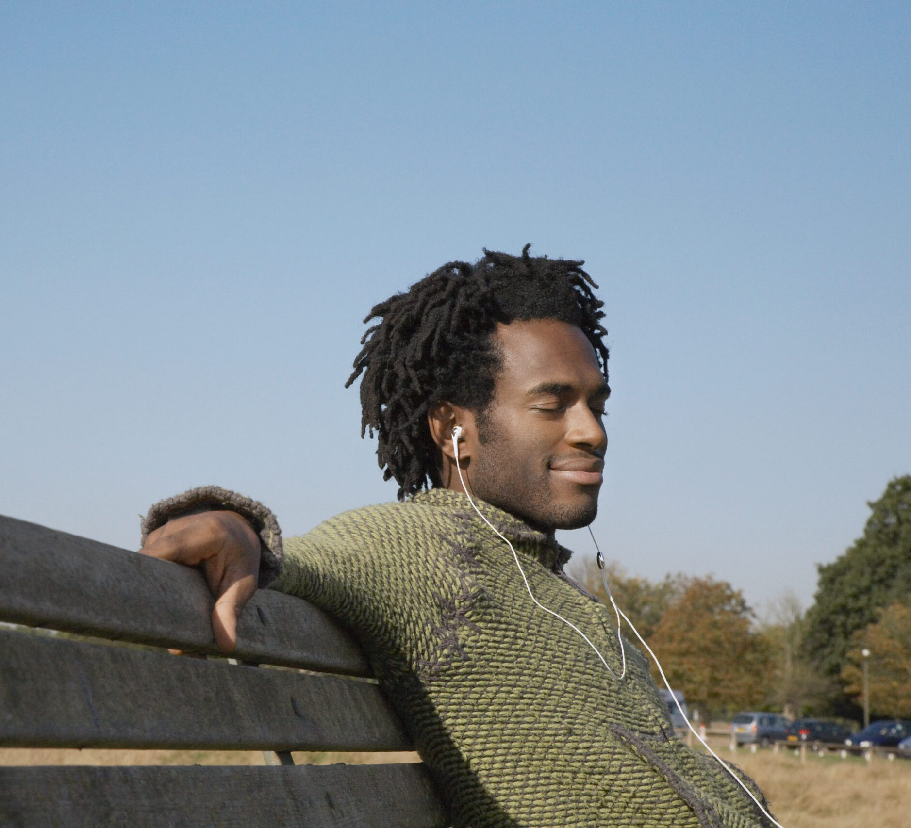 Young African American man listening to music while sitting on p