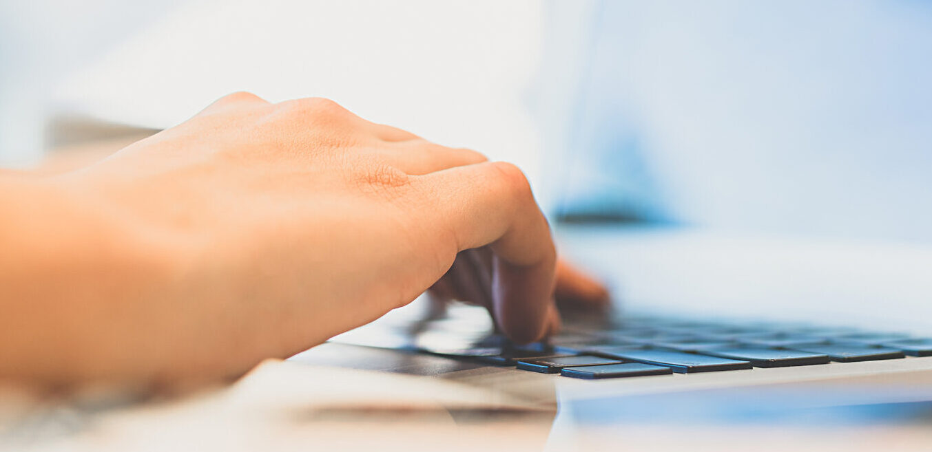 The hands work with a modern laptop